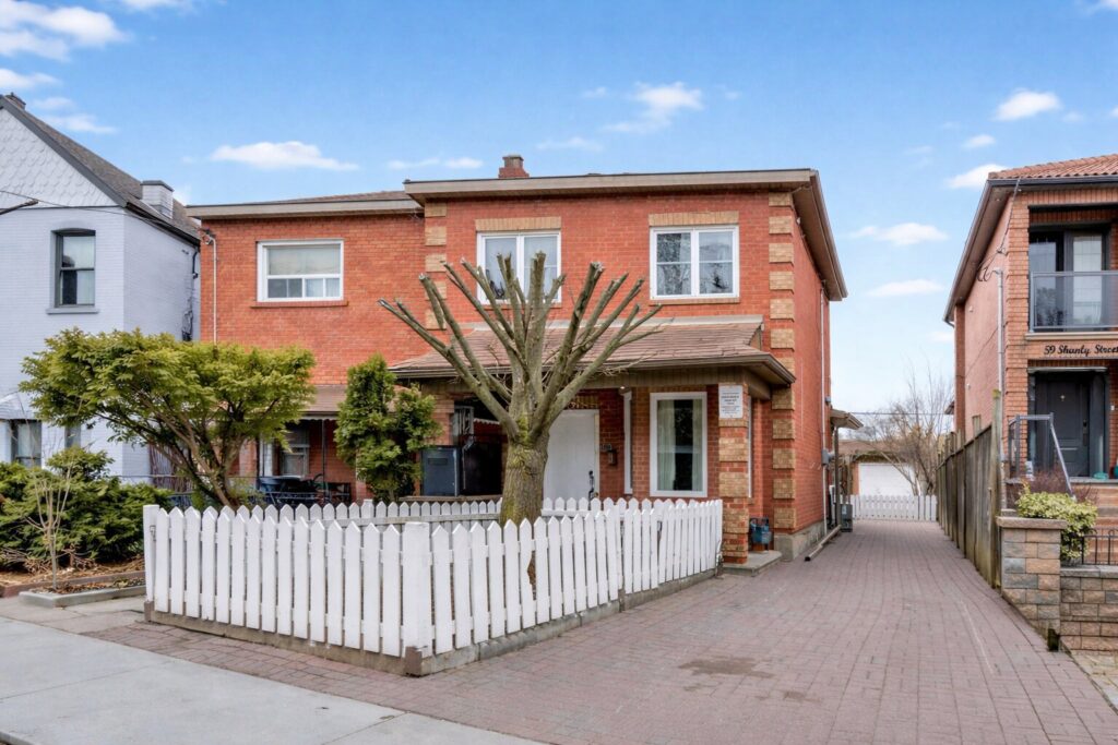 Side view of 57 Shanly St showing long driveway and white picket fence in front of house.