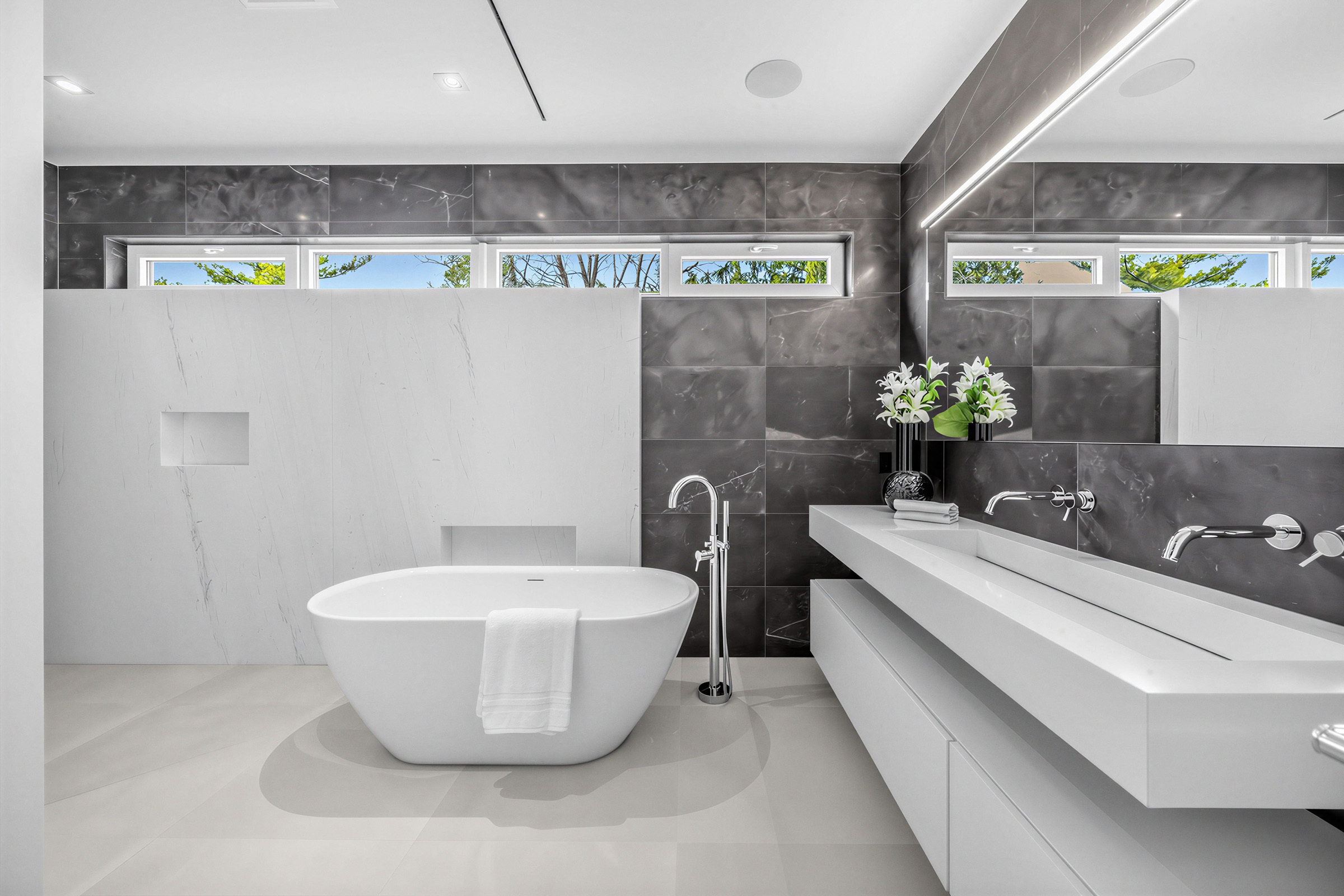 52 Burrows Ave – ensuite bath with freestanding soaker tub, integrated sink, wall-mounted faucets, floating cabinets, wide vanity, and four clerestory windows.