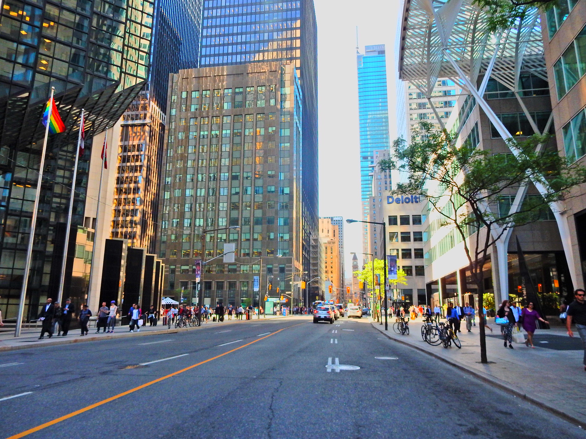 Street-level shot of Toronto's Financial District with cars, pedestrians on sidewalks and tall office buildings.