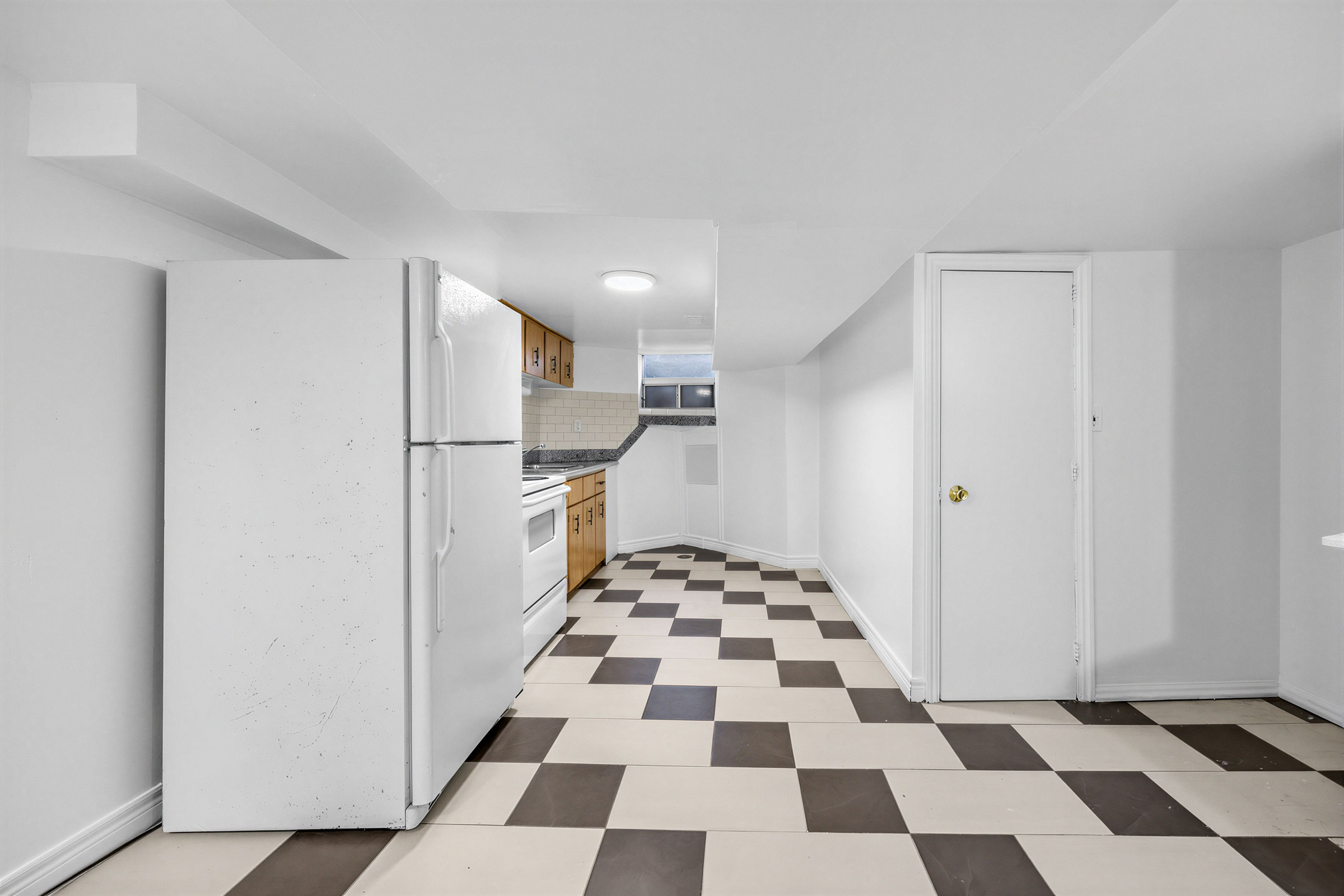 Basement kitchen with checkered brown and beige tiles.