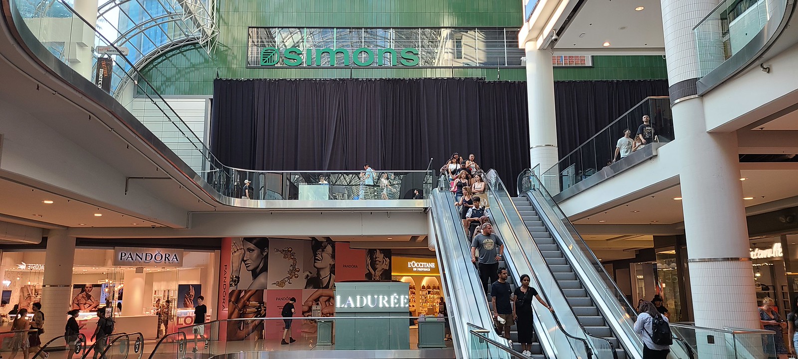 Simon's, Pandora, and people coming down escalator in Toronto Eaton Centre.