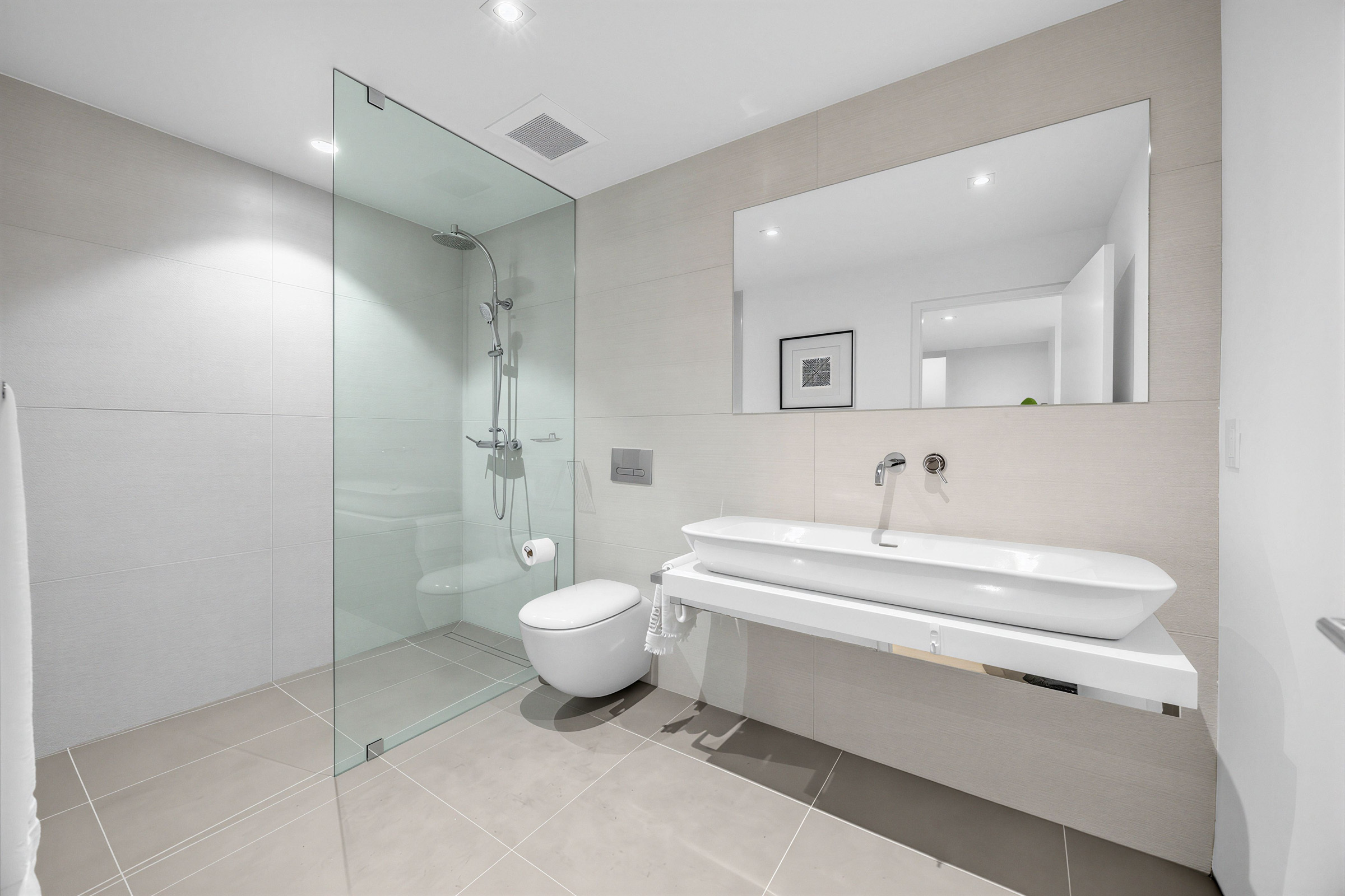 52 Burrows Ave 3-piece basement bath with trough sink, wall-mounted faucet, full-sized mirror, and walk-in shower with glass partition.