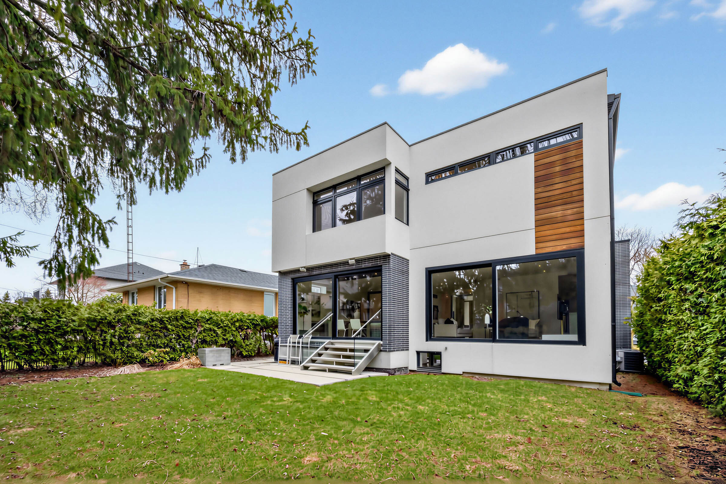 52 Burrows Ave backyard showing house, stone patio, lawn and greenery.
