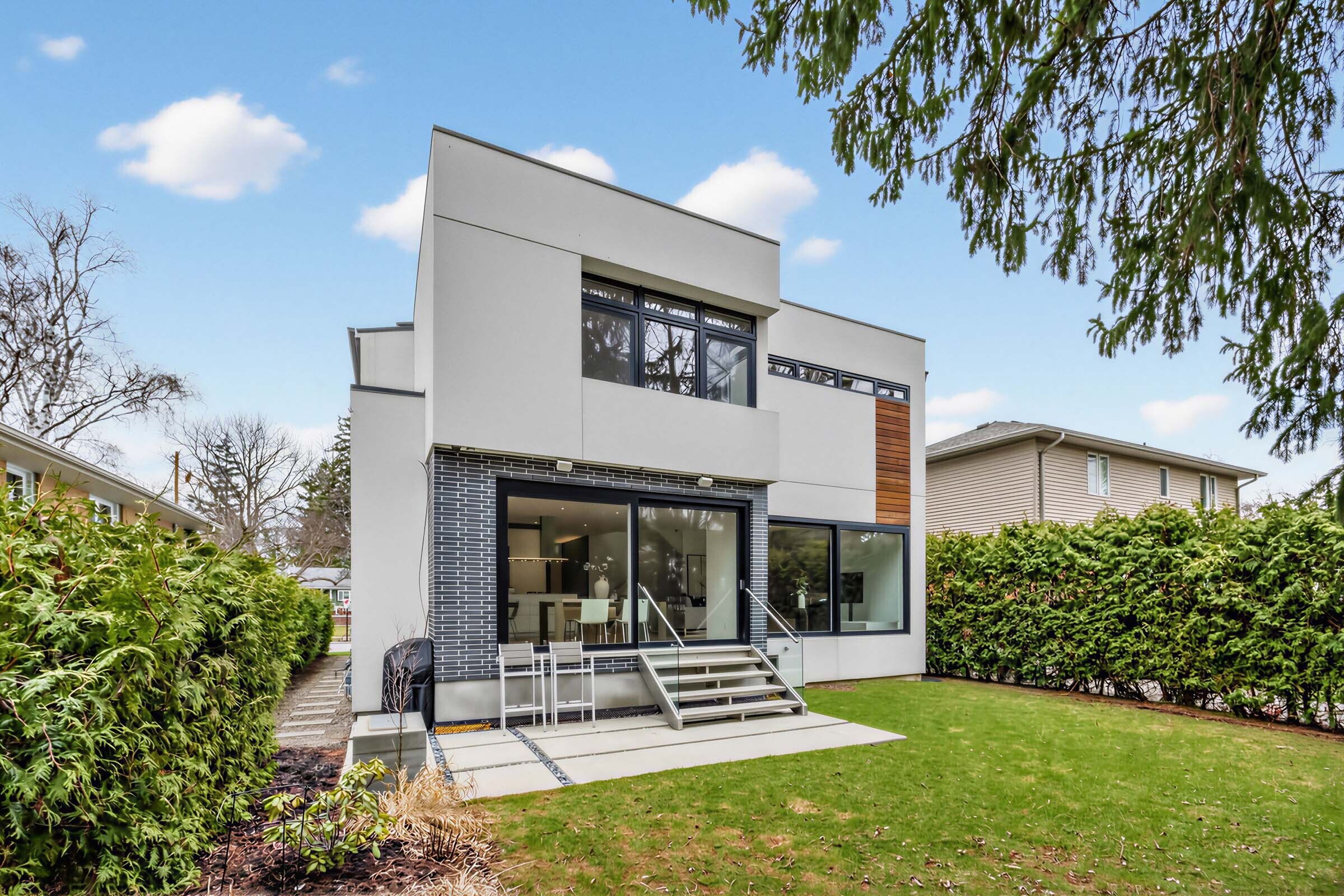 Backyard with thick privacy hedges on either side of house.