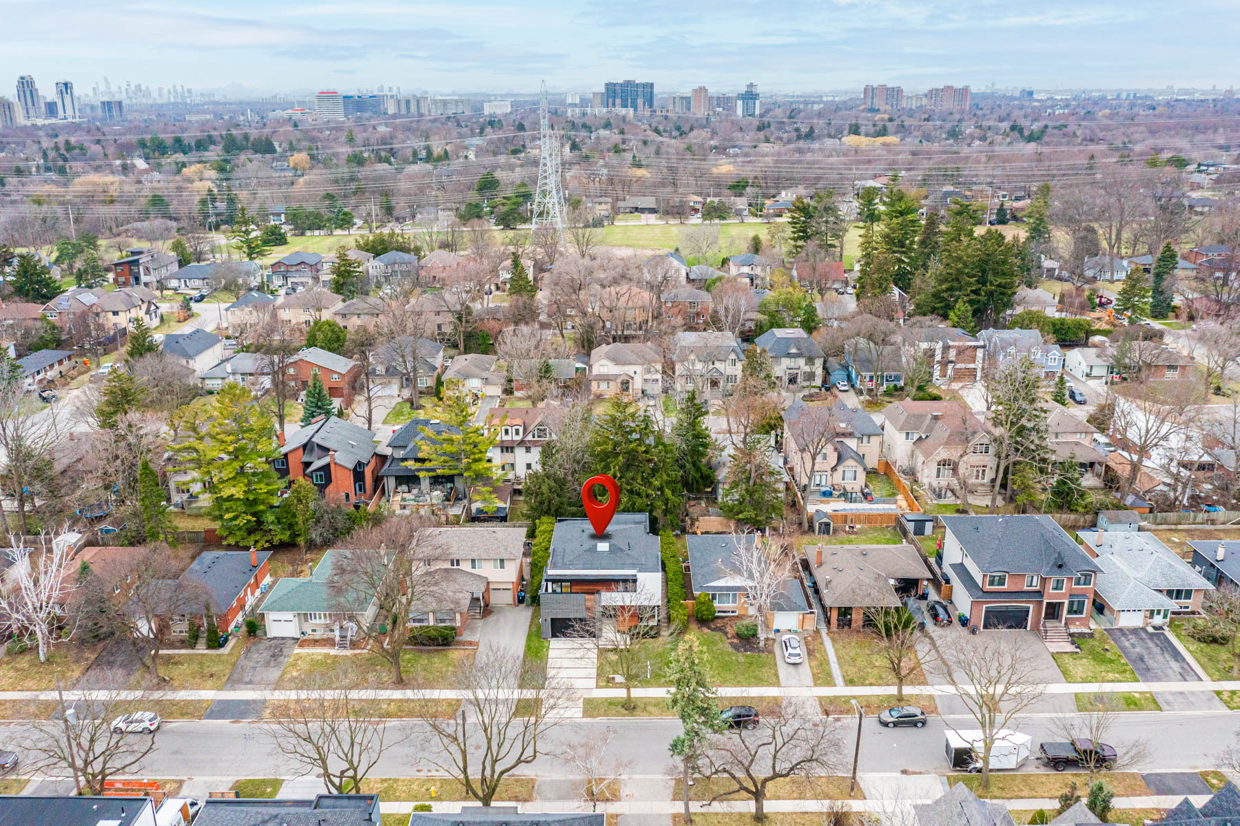 Aerial drone view with red location pin showing 52 Burrows, trees and streets, with greenery and communication towers in background.