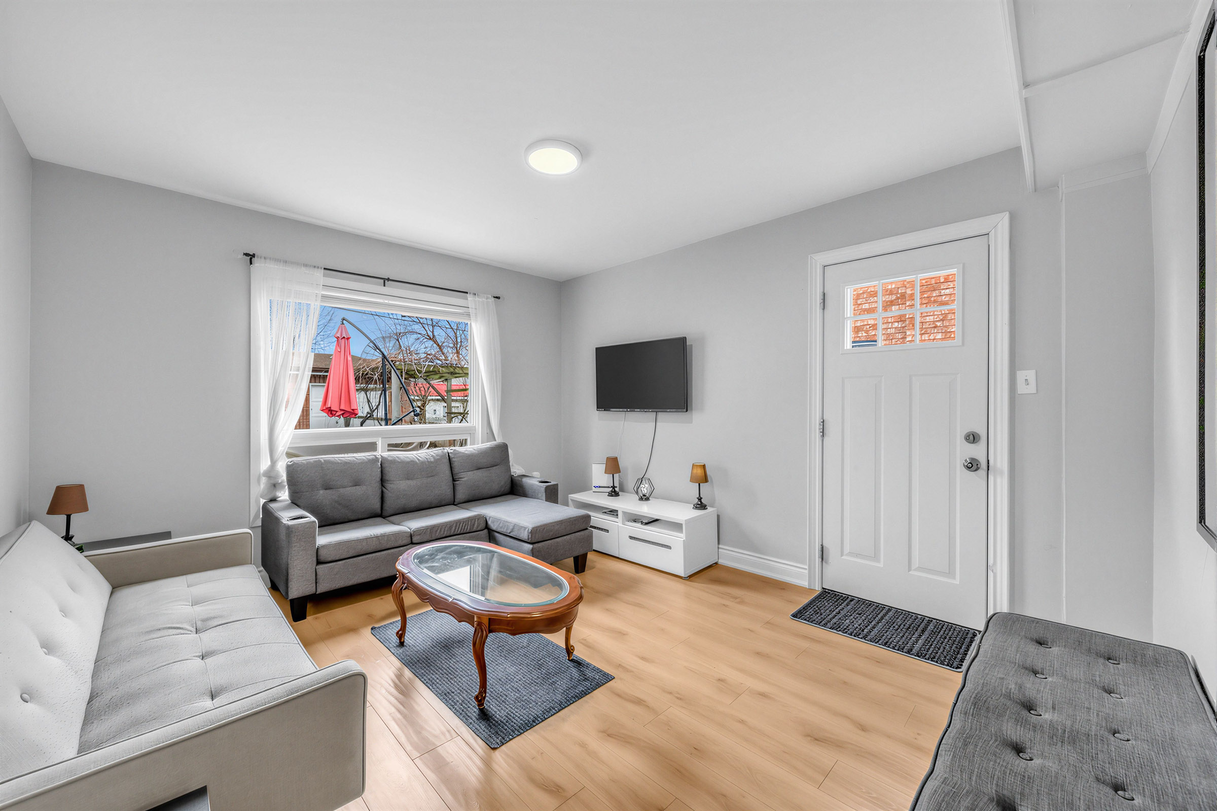 57 Shanly St living room with large window, gray walls, TV, furniture and laminate floors.