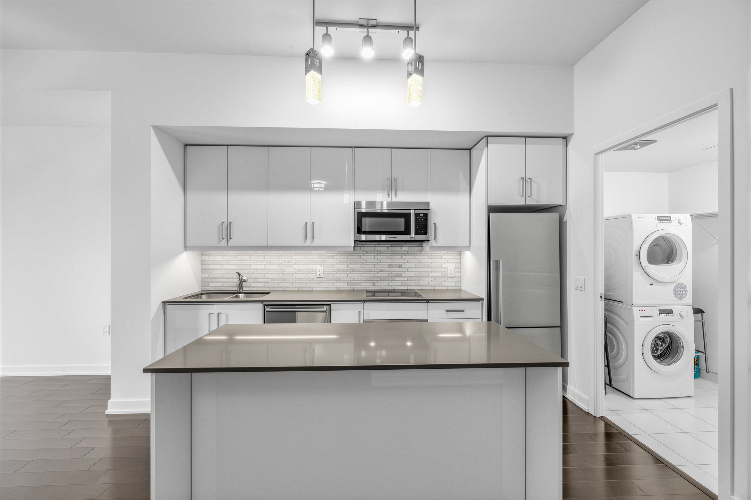 Rectilinear pendant lights with gold shades overhanging kitchen island.