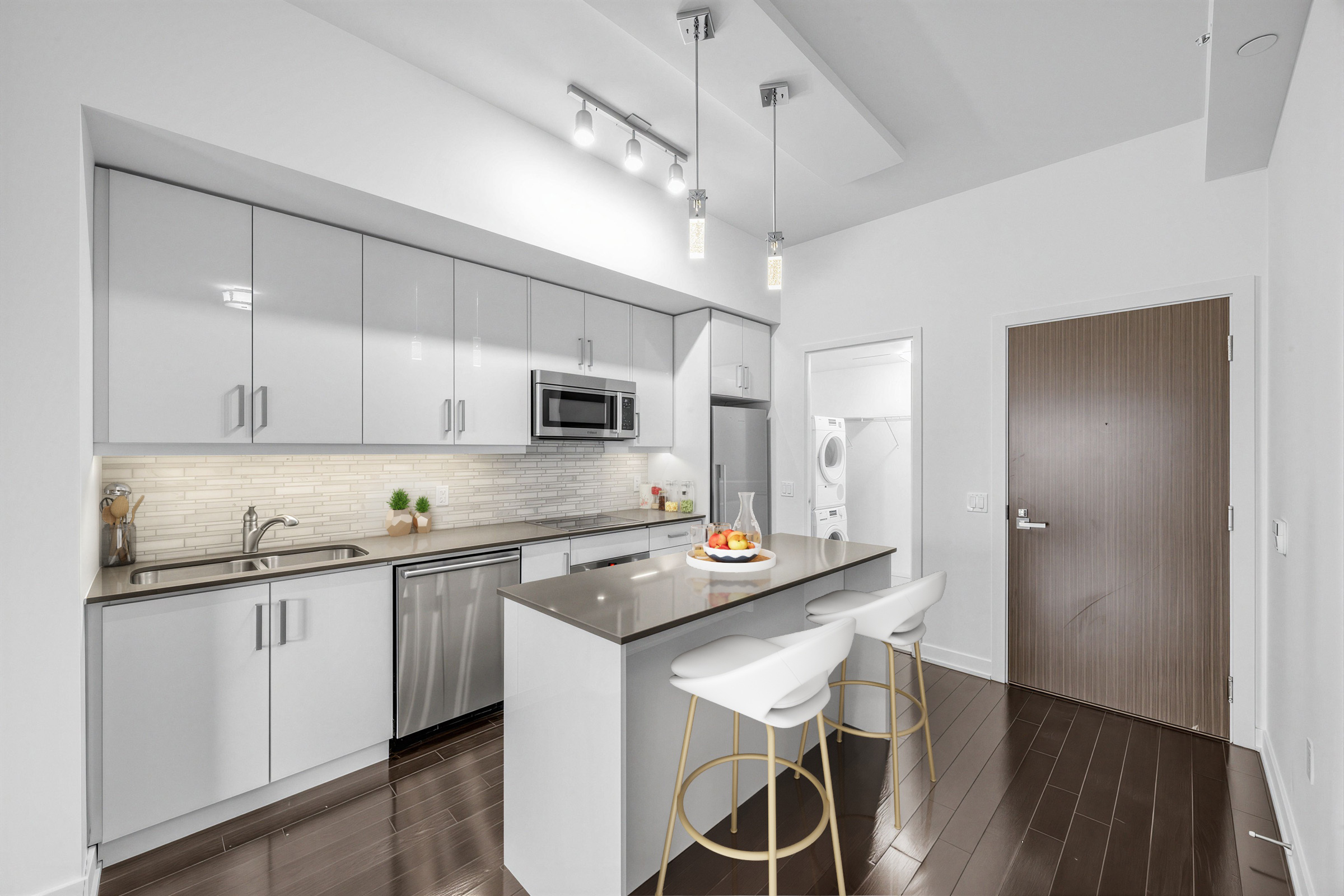 1 The Esplanade Unit 3403 kitchen island with dark Caesarstone countertop, white base and two chairs.