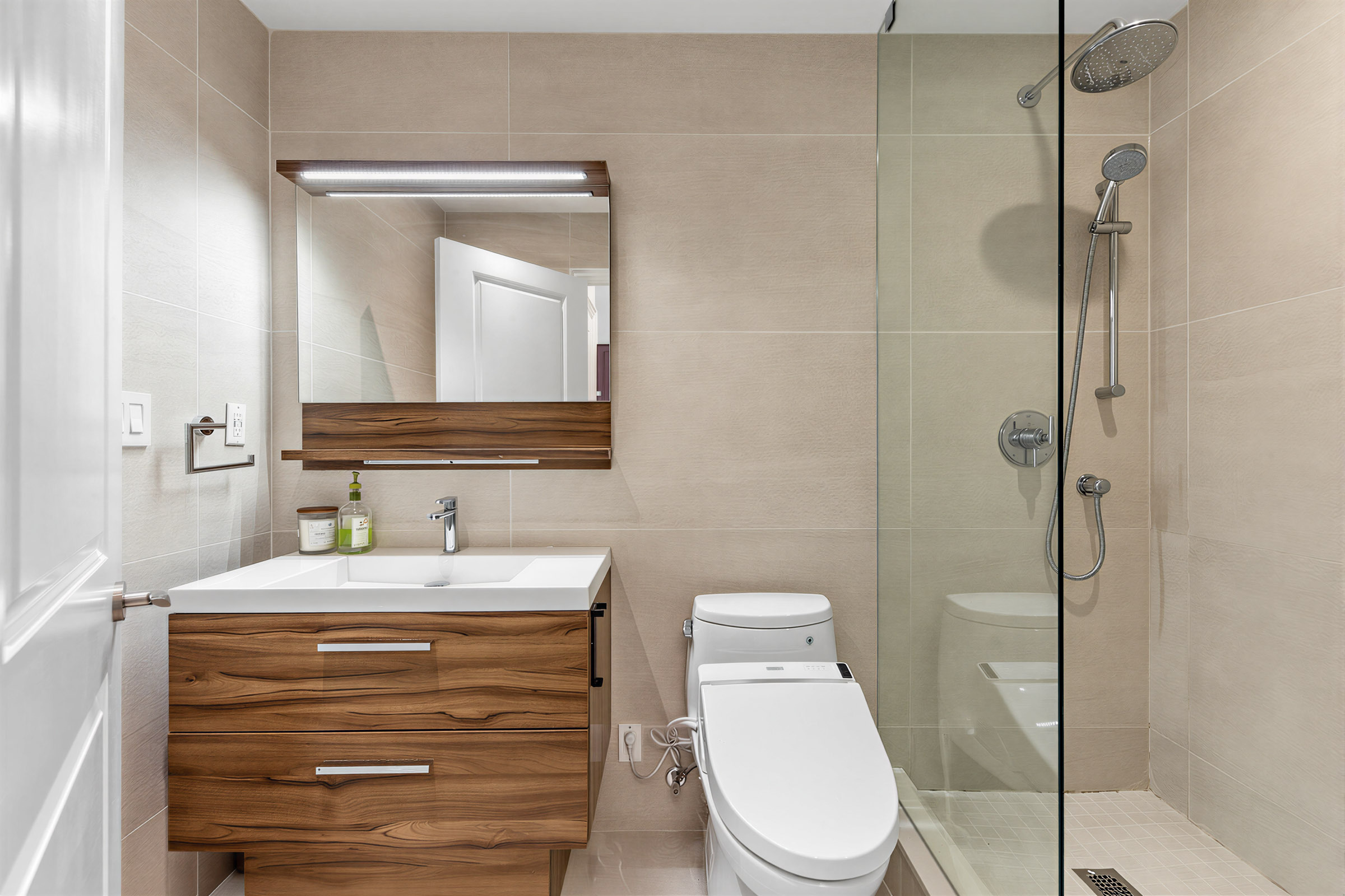 1 Bedford Rd Unit 603's renovated primary bathroom with large-format tiles, vanity with light fixture, ceramic sink with glossy drawers, and white Toto washlet.