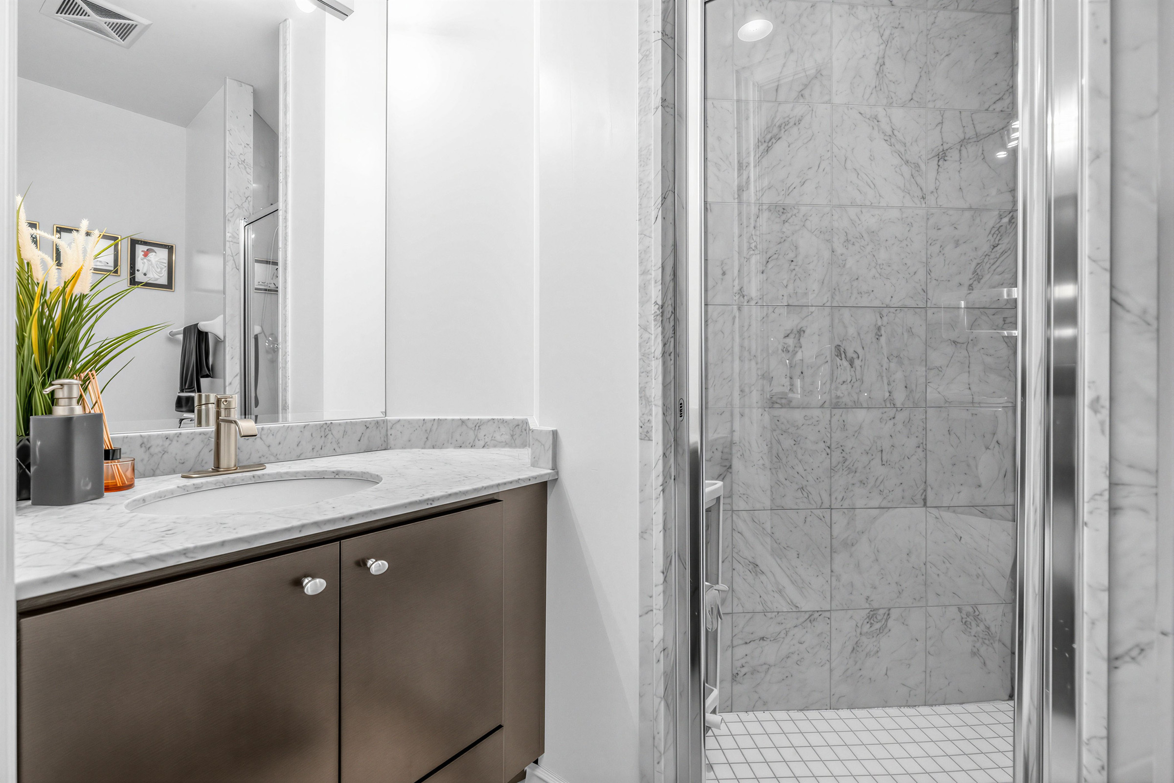 20 Bloorview Place Unit 1003's 3-piece 2nd bathroom with walk-in shower, gray tiles, vanity, storage cabinets, and brushed metal fixtures.