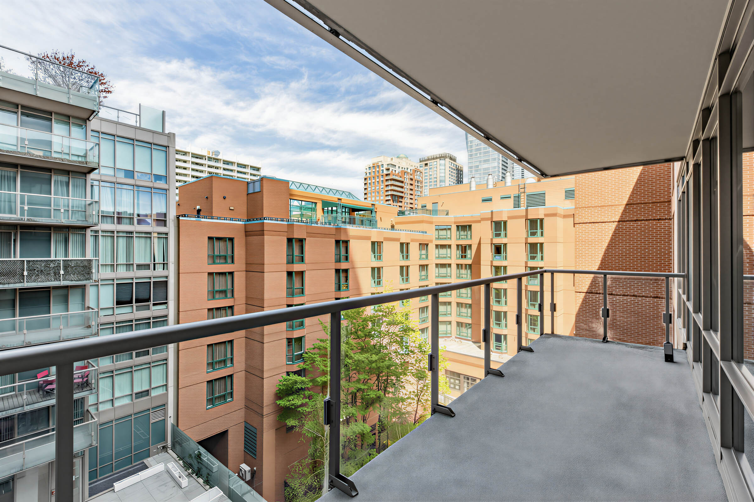 Condo balcony with clear glass panels overlooking courtyard.