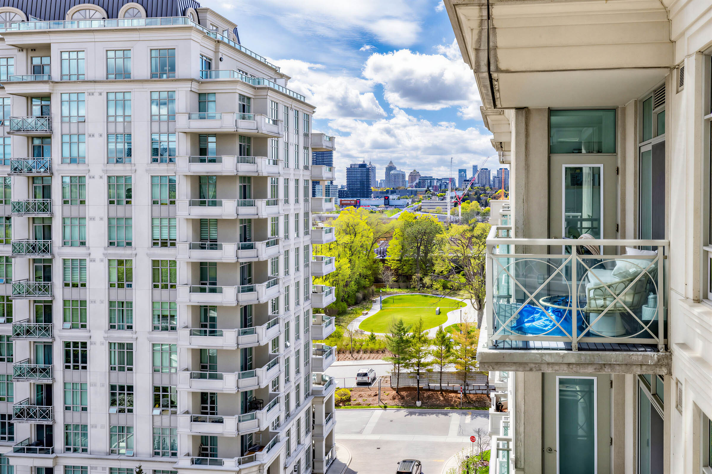 View of buildings, a park, mall and city skyline from condo balcony.