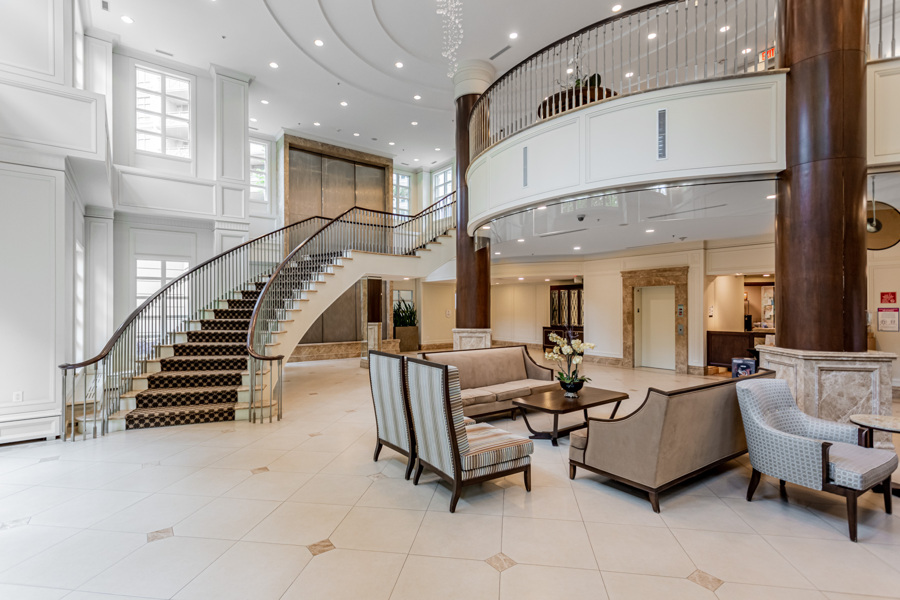 Aria Condos' sophisticated lobby with ornate furniture, decor, staircase and curved architectural elements.