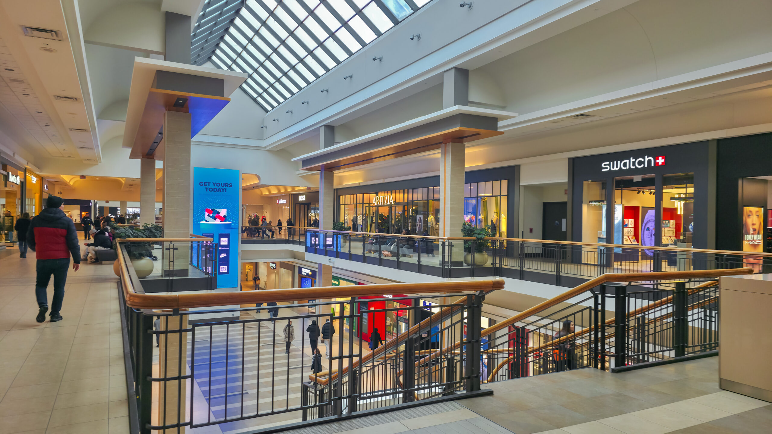 CF Fairview Mall showing people and stores like Swatch, Artizia and Roots.
