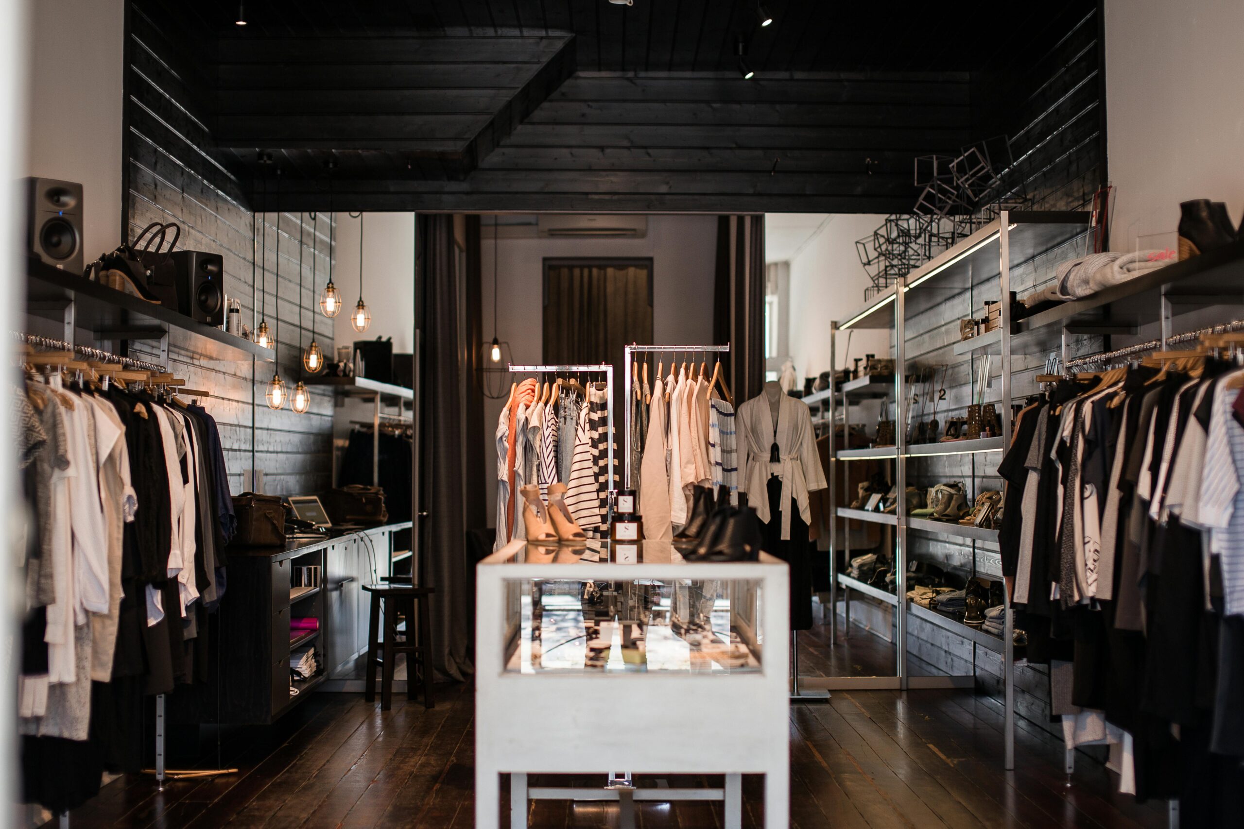 Interior of women's clothing store with clothes on racks and shoes on shelves.
