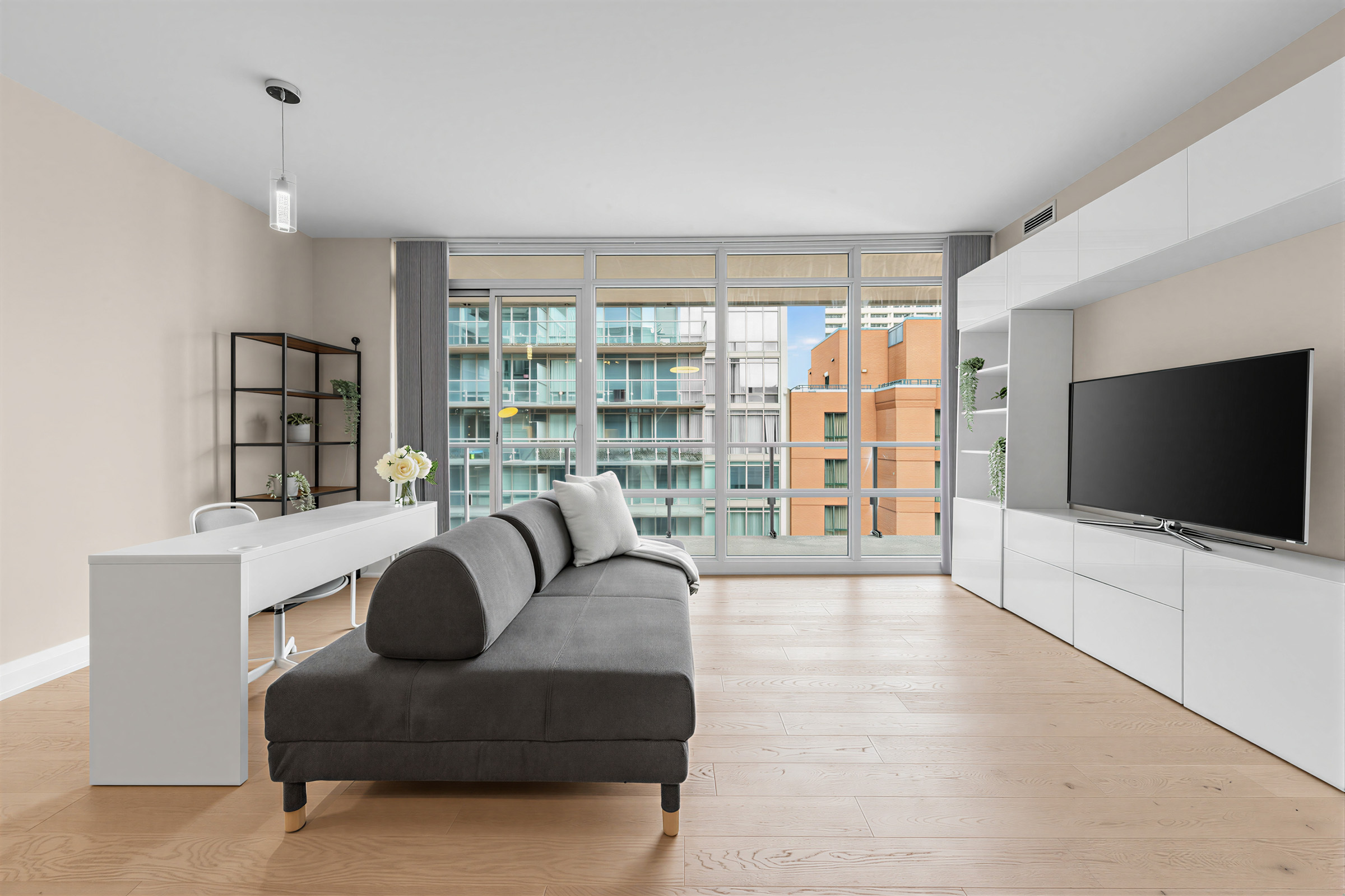 1 Bedford Rd Unit 603's open-concept living and dining room with furniture and large glass windows.