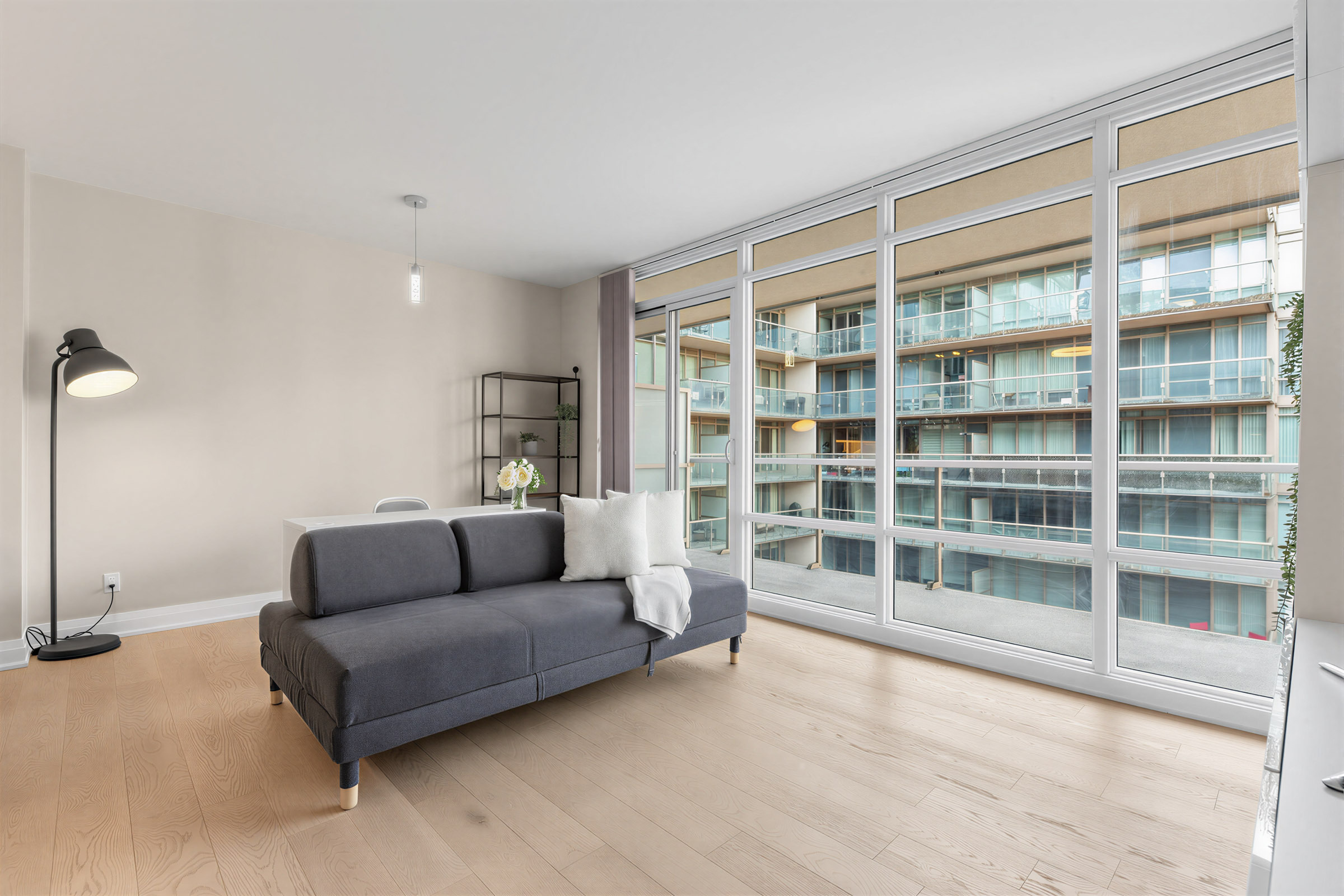 Condo living room with floor-to-ceiling, wall-to-wall glass windows with view of buildings.