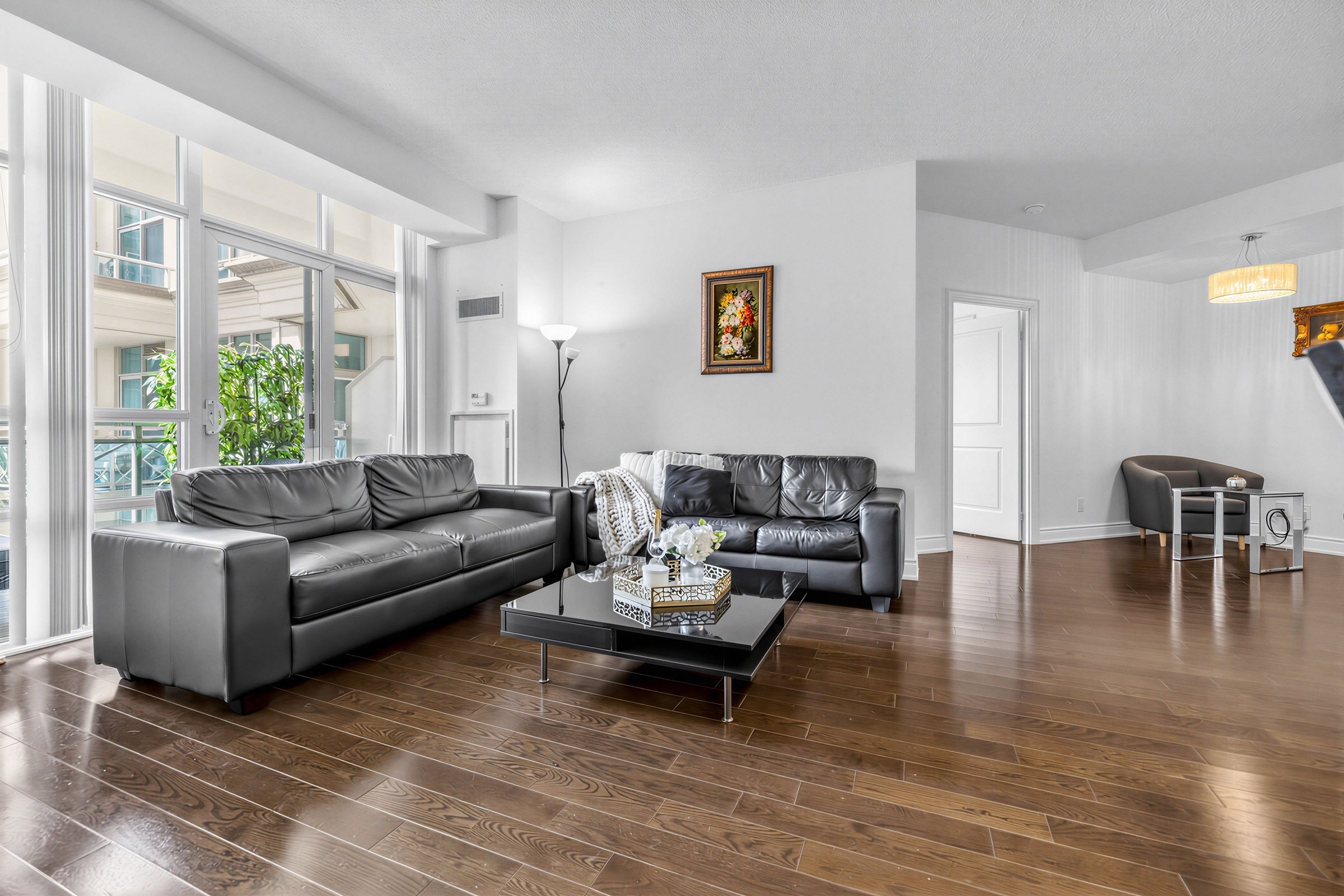 Brightly lit condo living room with angled balcony and furniture.