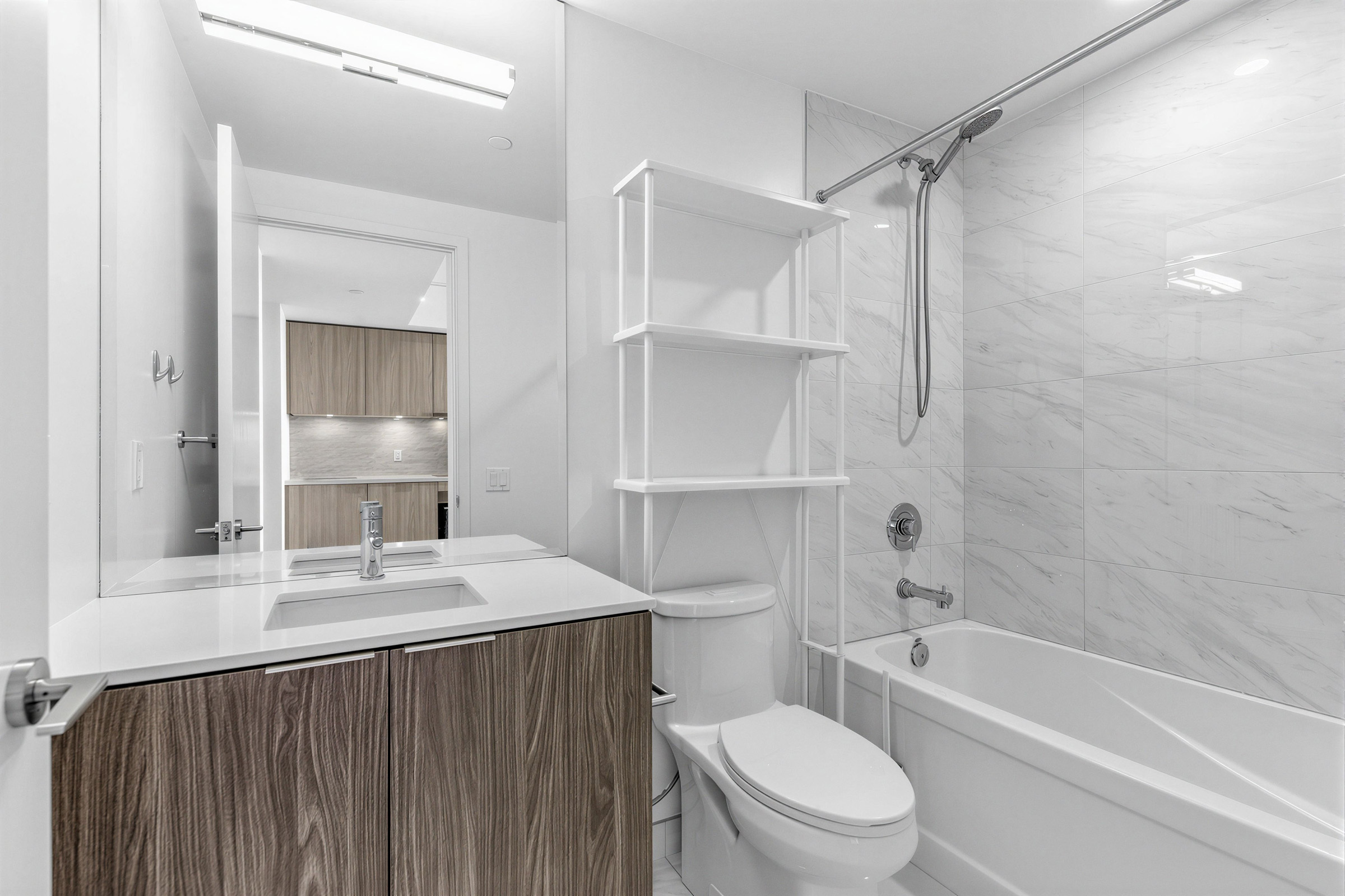 15 Queens Quay E Unit 1901 4-piece bath with soaker tub, sink, storage cabinet, porcelain tiles, over-the-toilet storage, and mirror-mounted lights.