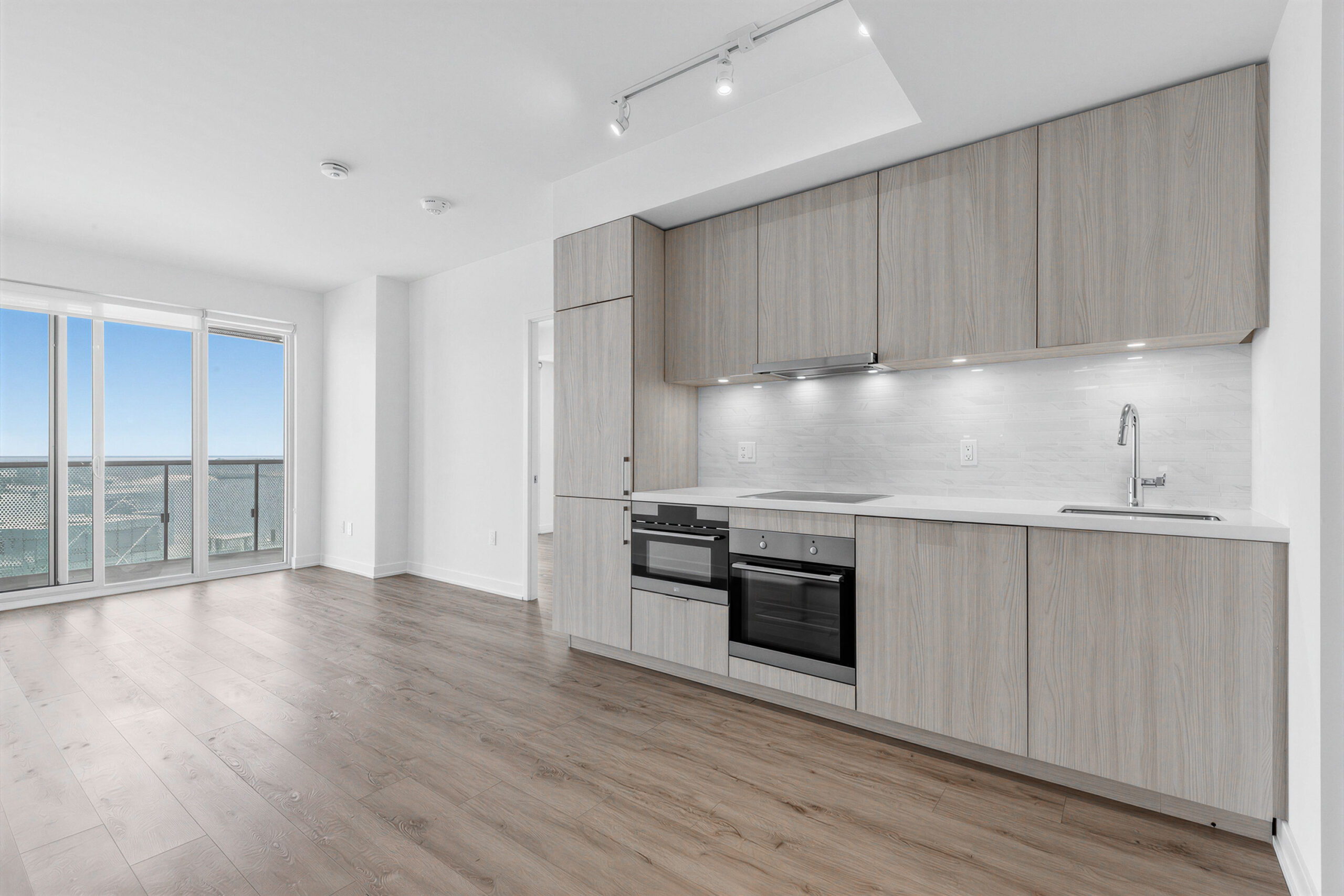 15 Queens Quay E Unit 1901 kitchen lit by balcony doors, track-lights and under-cabinet lights.