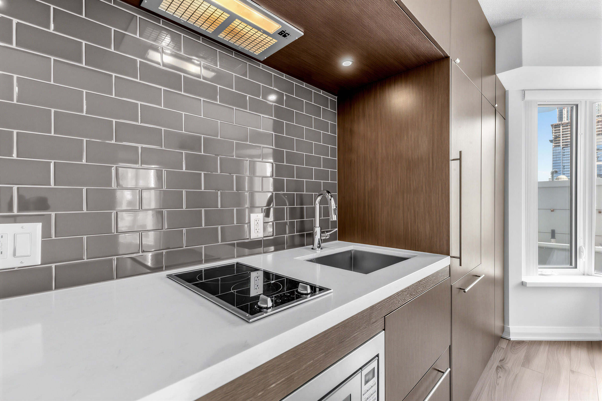 Side view of 155 Yorkville Ave Unit 1607's linear kitchen showing cabinets, appliances and bay windows.