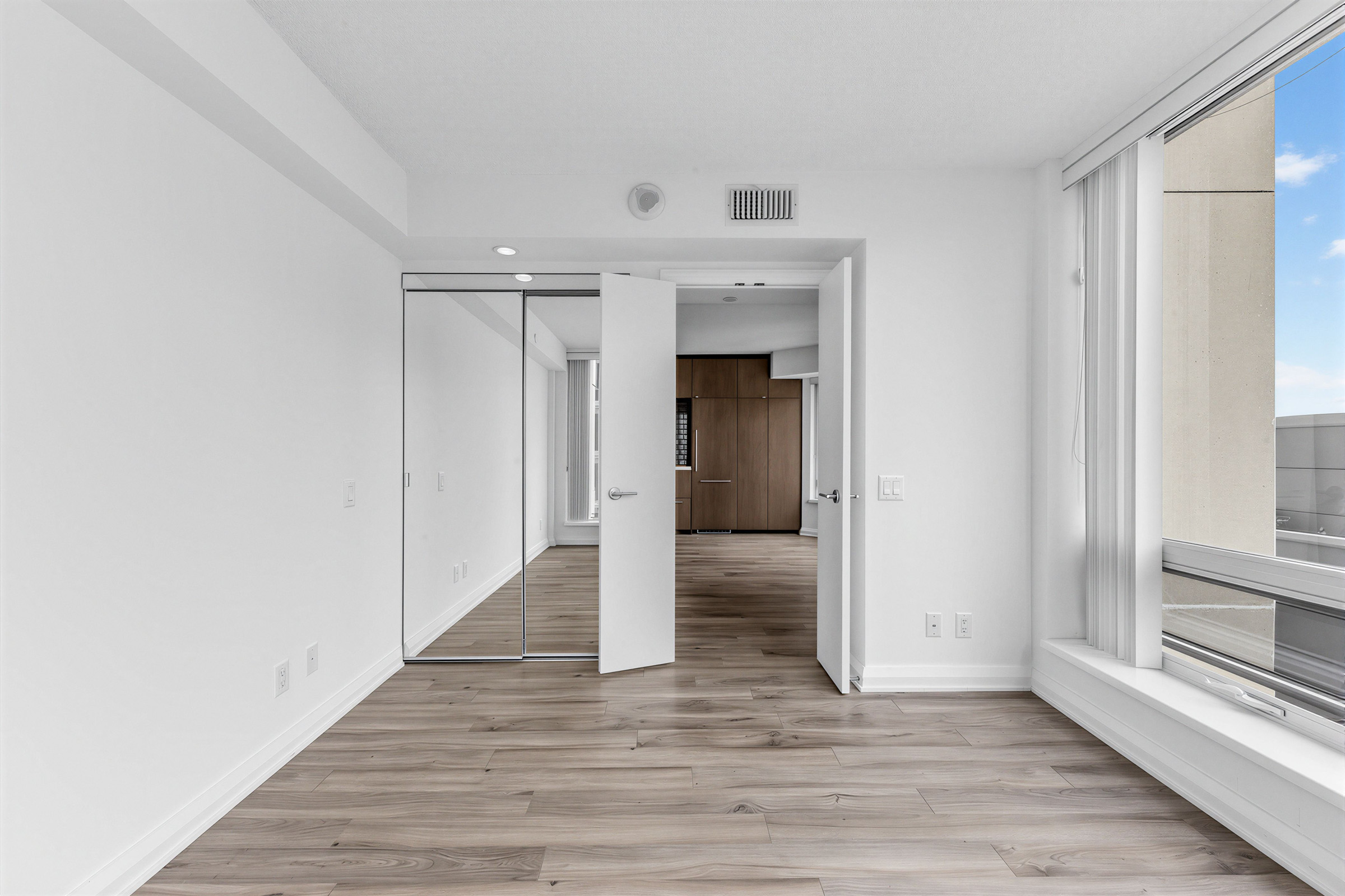 155 Yorkville Ave Unit 1607's primary bedroom with reflective mirror doors.
