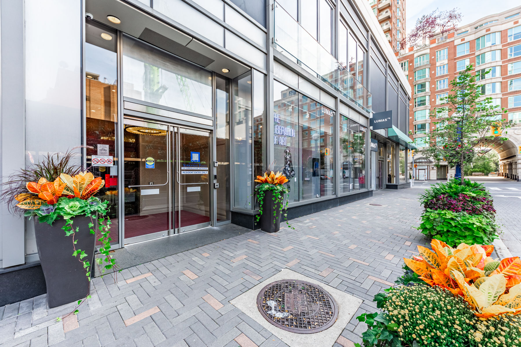 Exterior of 155 Yorkville Ave podium entrance with sign for LUMAS art gallery.