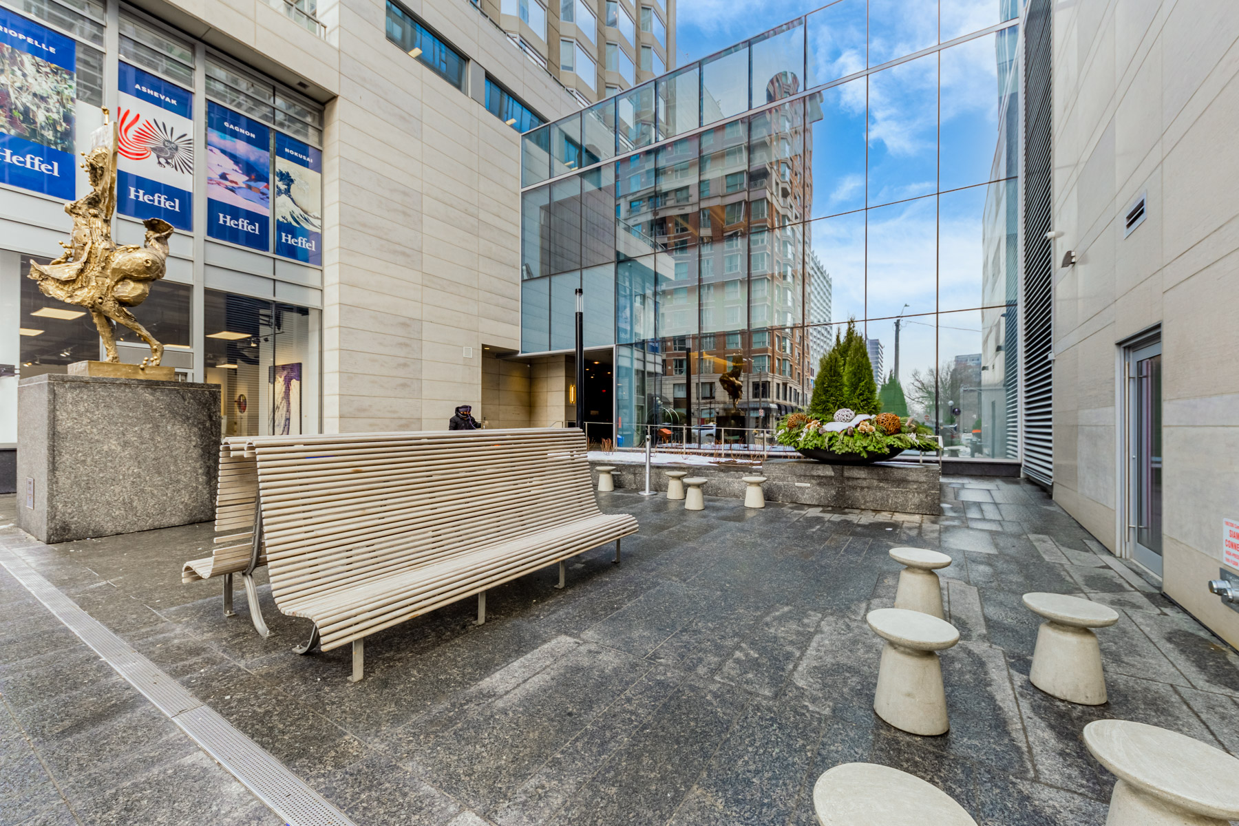 Yorkville Plaza courtyard with seating and large Figure Catching a Fly bronze statue.