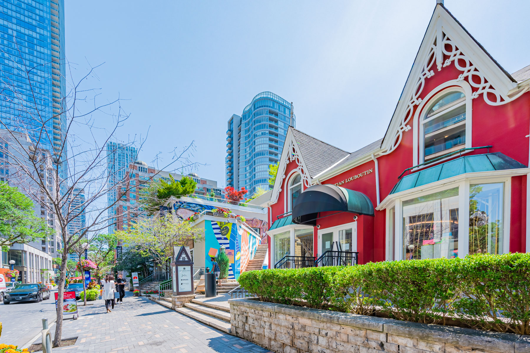 Christian Louboutin red storefront in Yorkville, Toronto with wide sidewalk and buildings in distance.