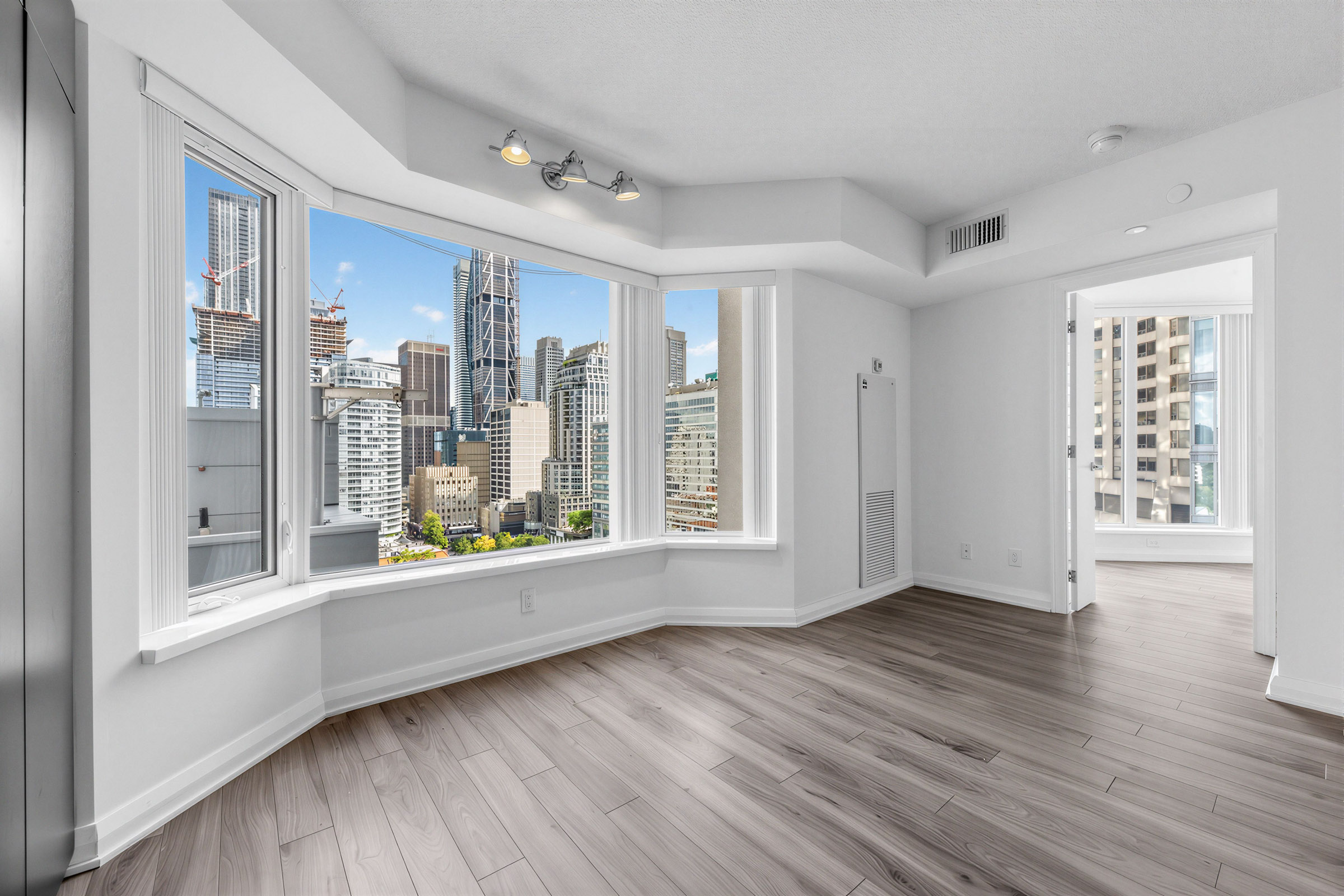 155 Yorkville Ave Unit 1607 living room with large bay windows showing view of Toronto.
